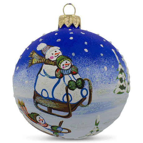 Glass Whimsical Snowman Sledding Between Trees - Blown Glass Ball Christmas Ornament 3.25 Inches in Blue color Round