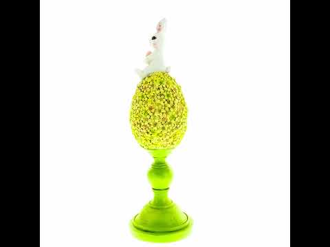 Figura de conejito posado sobre un huevo de Pascua floral